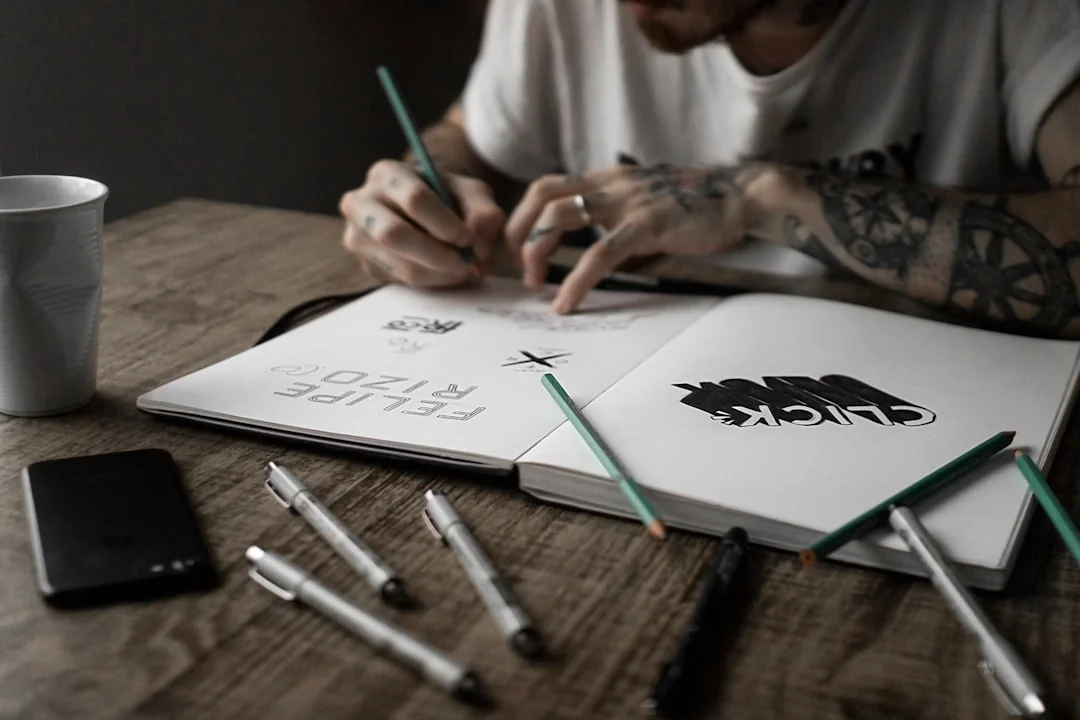 A top-down view of a minimalist workspace featuring a laptop and blank paper on a wooden table.